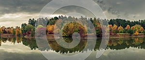 beautiful colorful autumn. picturesque panoramic view of the city park with multicolored trees reflected in the river in cloudy