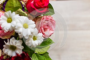 Beautiful colorful bouquet of flowers from roses, chamomiles and greenery on the table