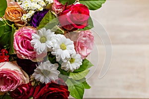 Beautiful colorful bouquet of flowers from roses, chamomiles and greenery on the table