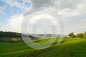 Krásne farebné oblaky nad zelenou lúkou počas východu alebo západu slnka.