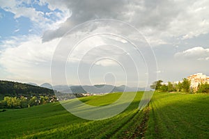 Krásne farebné oblaky nad zelenou lúkou počas východu alebo západu slnka.