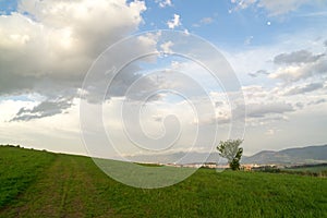 Krásne farebné oblaky nad zelenou lúkou počas východu alebo západu slnka.