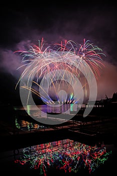 Beautiful colorful fireworks display on celebration night Celebration fireworks over the river with cityscape soft focus backgroun