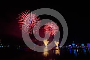 Beautiful colorful fireworks display on the urban lake for celebration on dark night background