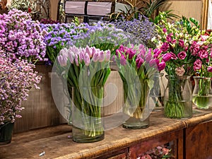 Beautiful colorful flowers for sale, placed in vases in flower shop. Tulips, roses and limonium