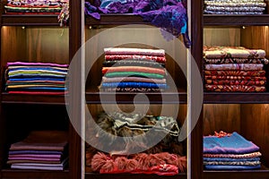 Beautiful colorful handmade pashmina shawls decorated with glittering precious stones and furs lie on the shop counters