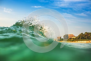 Beautiful colorful ocean wave crashing closing near sand beach