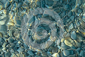 Beautiful colorful pebbles and big stone under turquoise blue clear water, scenic marine background or texture, top view