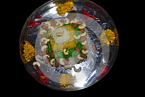 Beautiful colorful rice cake decorated with cashew nuts, almonds and flowers. steel pot, isolated black background