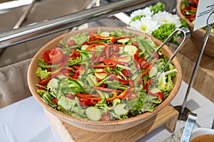 beautiful and colorful salad filled with lettuce greens cucumbers tomatoes red and green peppers at a catering event
