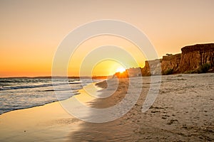 Beautiful colorful sunset in Algarve Portugal. Peaceful beach water and cliffs.