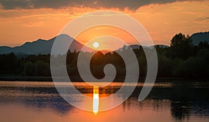 A beautiful, colorful sunset landscape with lake, mountain and forest. Natural evening scenery over the mountain lake in summer.