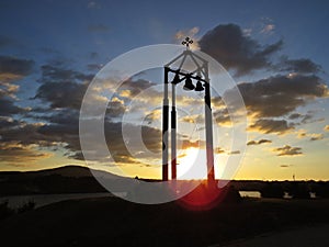 Beautiful Colorful Sunset Over Silhouette of Bell Tower with Cross and Four Bells
