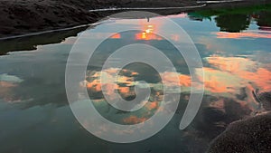 Beautiful colorful sunset reflected in river. Peaceful natural background with sun glow at dusk. Sun light and orange