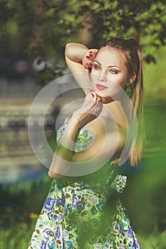 Beautiful colorful toned portrait of sensual young sportive woman with emotional eyes and long hair, in floral dress, standing in