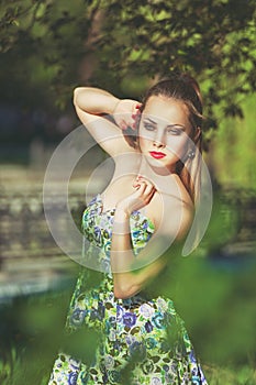 Beautiful colorful toned portrait of sensual young sportive woman with emotional eyes and long hair, in floral dress, standing in