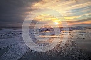 Beautiful winter landscape with frozen lake and sunset