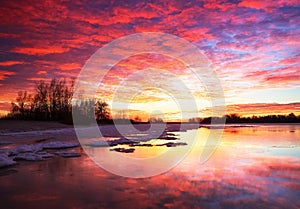 Beautiful colorful winter landscape with frozen lake and sunset