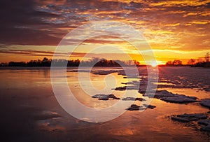 Beautiful winter landscape with frozen lake and sunset