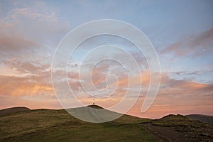 Beautiful colorful Winter sunset landscape over Latrigg Fell in Lake District with single person on hilltop admiring sunset photo