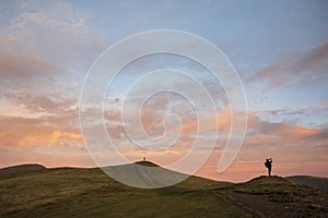 Beautiful colorful Winter sunset landscape over Latrigg Fell in Lake District with two people on hilltop admiring sunset photo