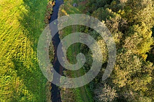 Beautiful colors of autumn. Forest, meadow and river photographed with a drone on sunny day.