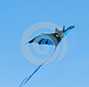 A beautiful, colourful stunt kite, in the blue sky, high up in the wind