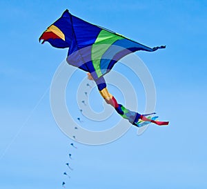 A beautiful, colourful stunt kite, in the blue sky, high up in the wind