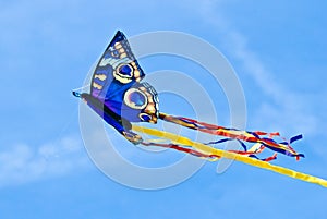 A beautiful, colourful stunt kite, in the blue sky, high up in the wind in form of a butterfly