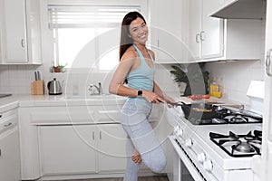 Beautiful commercial model fitness and healthy living portrait, cooking healthy low calorie meal on stove top after exercising