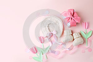 Beautiful composition with baby booties shoes, bonnet and gift box on pink background. Concept of baby shower party, pregnancy,