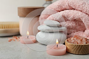 Beautiful composition with burning candles and different spa products on light grey table, closeup