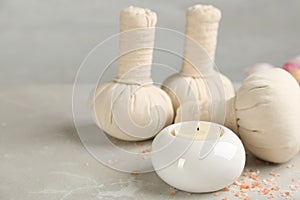 Beautiful composition with candle and spa herbal bags on marble table. Space for text