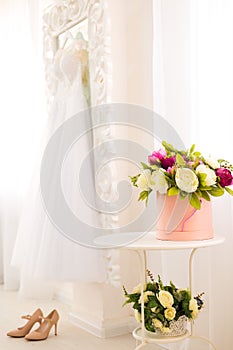 Beautiful composition with colorful peonies in a round box, high heels and wedding dress