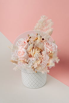 A beautiful composition of dried flowers in a ceramic vase. A bouquet of stabilized roses and flax in a delicate palette.