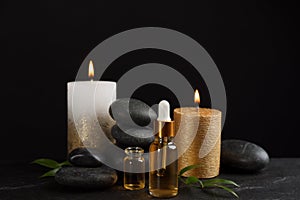 Beautiful composition with essential oil, spa stones and candles on black table