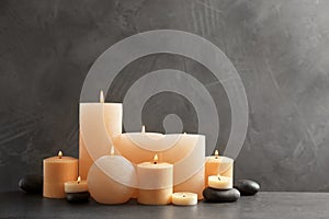 Beautiful composition with lit candles and spa stones on table