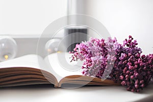 Beautiful composition with opened book and lilac flowers. Romantic wallpaper.