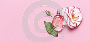 Beautiful composition with perfume and flowers. Perfume bottles, rose flowers petals green leaves on pink background top view Flat