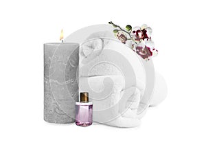 Beautiful composition with rolled towels, orchid flowers and burning candle on white background. Spa therapy