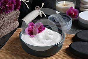 Beautiful composition with sea salt, burning candle, flowers and different spa products on grey table