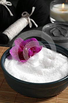 Beautiful composition with sea salt, burning candle, flowers and different spa products on grey table, closeup