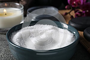 Beautiful composition with sea salt, burning candle, flowers and different spa products on grey table, closeup