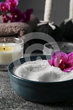 Beautiful composition with sea salt, burning candle, flowers and different spa products on grey table, closeup