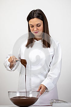 Beautiful confectioner pouring dark melted chocolate, isolated white background