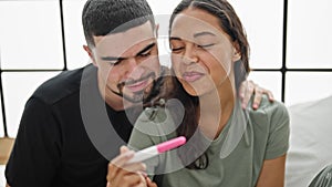 Beautiful confident couple in love, smiling and hugging, holding positive pregnancy test in their cozy bedroom, joyfully expecting
