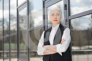 Beautiful confident senior businesswoman standing with crossed arms and looking at camera