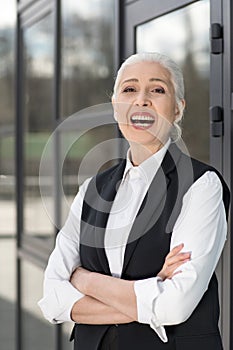 Beautiful confident senior businesswoman standing with crossed arms and looking at camera