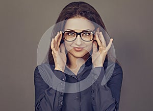 Beautiful confident thinking smiling business brunette woman holding two hands the glasses on the face in blue shirt on grey photo