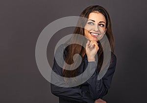 Beautiful confident thinking smiling business woman with folded arms looking up in blue shirt on grey background with empty copy